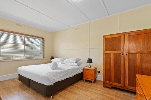 een slaapkamer met een bed en een houten kast bij The Fishermans Cottage in Lakes Entrance