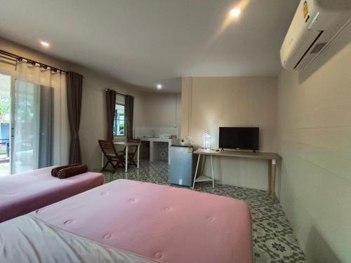 um quarto com 2 camas e uma secretária com uma televisão em บ้านในสวนรีสอร์ทBannnaisuan Resort em Prachuap Khiri Khan