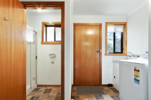 ein Badezimmer mit einem Waschbecken und einer Holztür in der Unterkunft Deppelers in Lakes Entrance