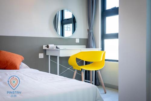 a bedroom with a yellow chair and a mirror at Jesselton Quay by Pinstay in Kota Kinabalu