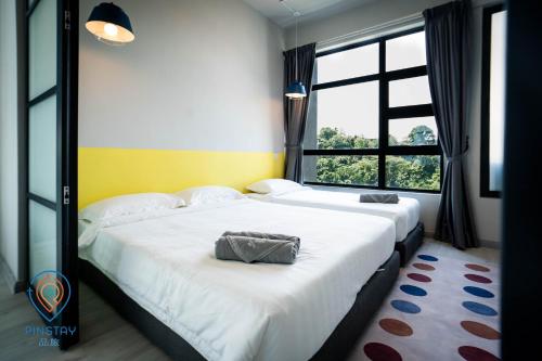 two beds in a room with a large window at Jesselton Quay by Pinstay in Kota Kinabalu