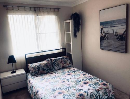 - une chambre avec un lit doté d'un couvre-lit floral et d'une fenêtre dans l'établissement Renas Court, Unit 6, 72 Little Street, à Forster