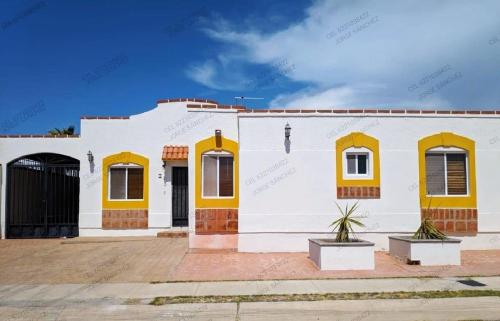 a white building with yellow doors and windows at Casa Villa Serena 4 in San Carlos