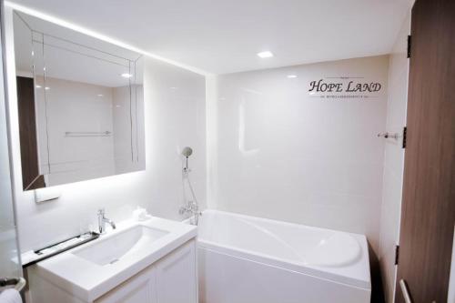 een witte badkamer met een wastafel en een spiegel bij Hope Land Hotel Sukhumvit 8 in Bangkok