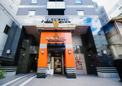 una entrada a un edificio de apartamentos con una puerta naranja en APA Hotel Midosujihonmachieki Higashi en Osaka