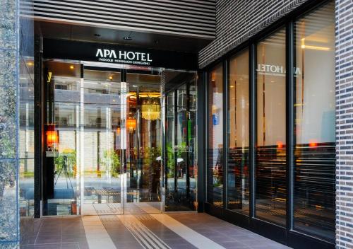ein Geschäft vor einem Gebäude mit Glastüren in der Unterkunft APA Hotel Midosujihonmachieki Higashi in Osaka