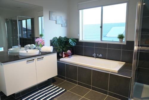 a bathroom with a tub and a sink at Classic 6BRM Villa in Melbourne in Laverton