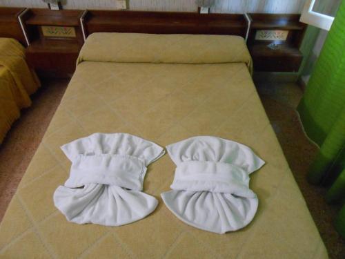 dos toallas blancas están sentadas en una cama en el Hotel Danubio en Villa Gesell