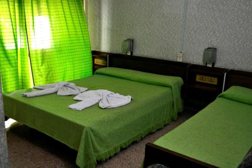 a bedroom with two beds with green sheets and towels at Hotel Danubio in Villa Gesell