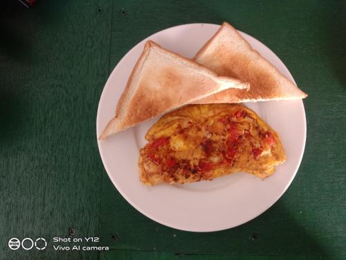 un plato blanco con un trozo de pizza y dos trozos de pan en Yayan Bungalow, en Gili Air