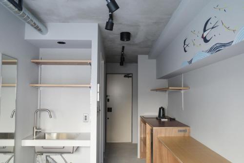 a kitchen with white walls and a sink and shelves at ART HOTELS SHIBUYA in Tokyo
