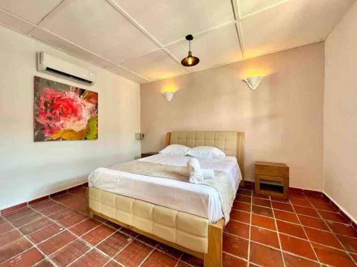 a bedroom with a bed and a painting on the wall at 5br COZY HOUSE ROOFTOP POOL AC OLD CITY in Cartagena de Indias