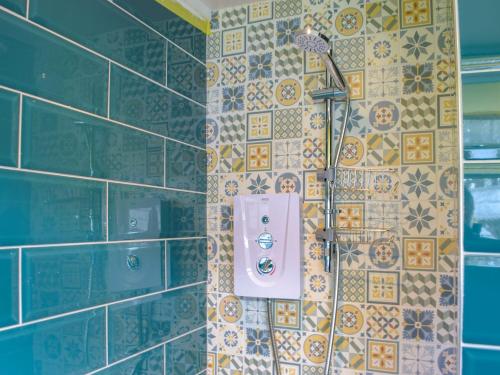 a bathroom with a shower with a tile wall at Ty Haf in Roch