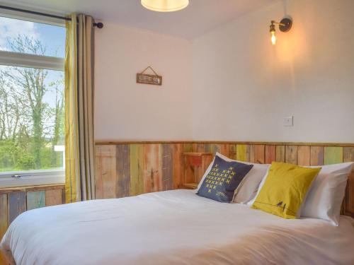um quarto com uma cama branca com almofadas e uma janela em Ty Haf em Roch