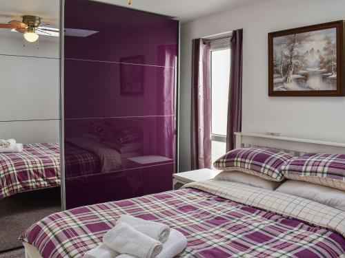 Habitación púrpura con 2 camas y espejo. en Thistle Dew en Great Yarmouth