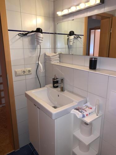 La salle de bains blanche est pourvue d'un lavabo et d'un miroir. dans l'établissement Schöne Wohnung in der Nähe von Schwäbisch Hall, à Rieden