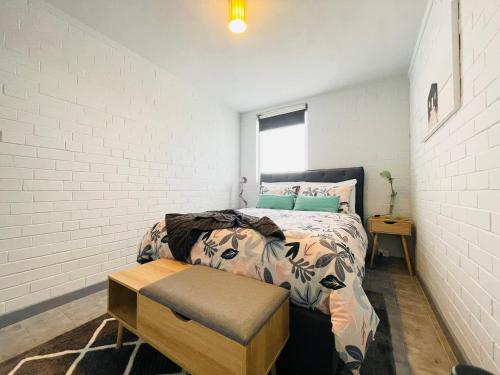 a bedroom with a bed and a white brick wall at Port Vista - Central Fremantle Apartment in Fremantle