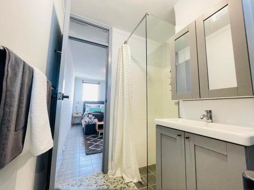 a bathroom with a sink and a glass shower at Port Vista - Central Fremantle Apartment in Fremantle