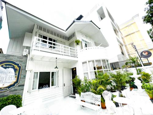 een wit huis met witte stoelen ervoor bij RoomQuest Rim Praya Dinsor Road in Bangkok