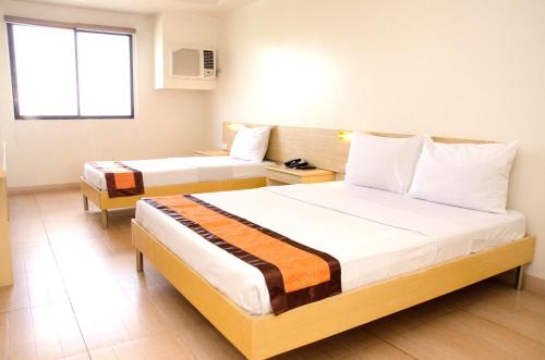 Habitación de hotel con 2 camas y ventana en M Suites Hotel, en Manila