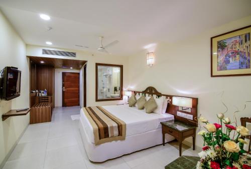 a hotel room with a bed and a television at La-Paz Gardens Beacon Hotel - Vasco da Gama Goa in Vasco Da Gama
