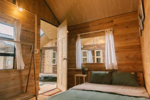 a bed in a wooden room with a window at Lacasa home&coffee Mộc Châu in Mộc Châu