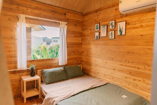 a room with a bed in a wooden room with a window at Lacasa home&coffee Mộc Châu in Mộc Châu