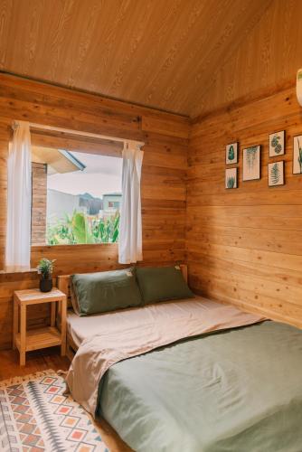 a bed in a wooden room with a window at Lacasa home&coffee Mộc Châu in Mộc Châu