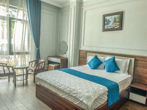 a bedroom with a bed with blue pillows at Khách sạn Hoàng Minh Châu Mỹ Phước in Bến Cát