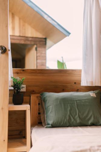 a bed with a green pillow and a window at Lacasa home&coffee Mộc Châu in Mộc Châu