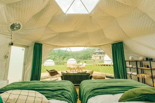 a bedroom with two beds and a large window at 温泉グランピングWooods芸北 