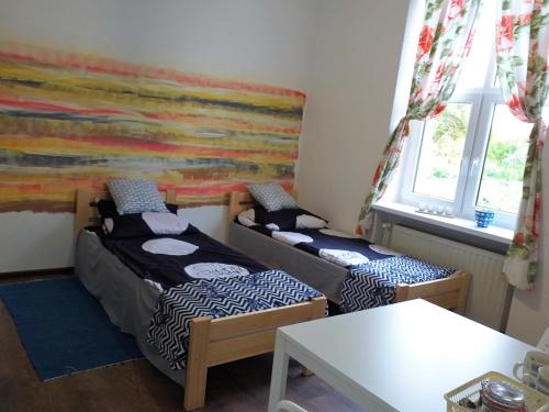 Habitación con 2 camas, mesa y ventanas. en Pokoje przy trasie S-7 Zajezierze 8 14-330, en Małdyty