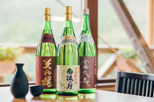 três garrafas de vinho sentadas numa mesa em 温泉グランピングWooods芸北 