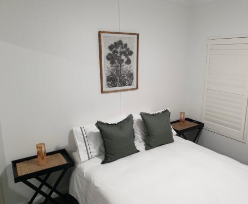 1 dormitorio con 1 cama blanca y 2 mesas en The Tribe House Kiama, en Kiama