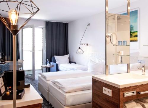 - une chambre d'hôtel avec un lit et un miroir dans l'établissement Dorint Hotel Düren, à Düren