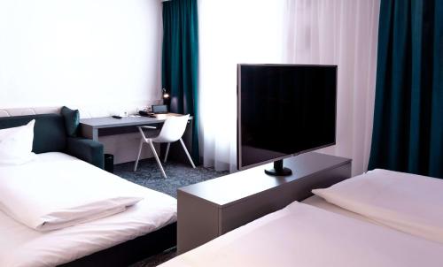 a hotel room with two beds and a television at Dorint Hotel Düren in Düren - Eifel