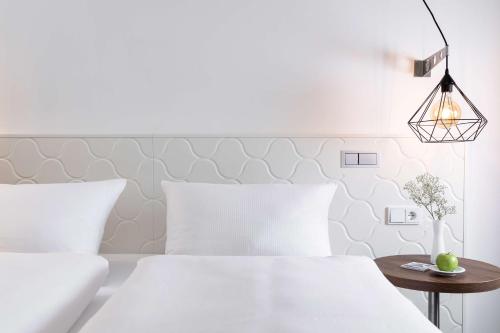 a white bedroom with two beds and a table at Dorint Hotel Düren in Düren - Eifel
