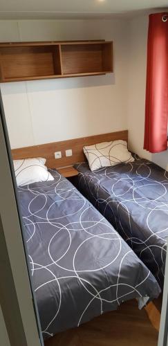 LitteauにあるMOBILHOME CLIMATISE TOUT CONFORT 6 à 8 PERSONNES à louerのベッド2台が隣同士に設置された部屋です。
