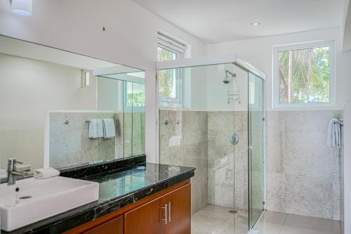 a bathroom with a glass shower and a sink at Villa Tankah Mandala in Tulum
