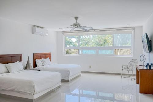 a white room with two beds and a window at Villa Tankah Mandala in Tulum