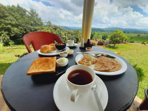 a black table topped with plates of food and a cup of coffee at The Arcadia Pool and Villa - Umroi in Shillong