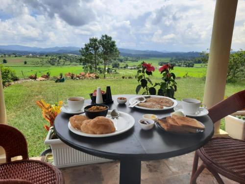a table with food on it with a view of a field at The Arcadia Pool and Villa - Umroi in Shillong