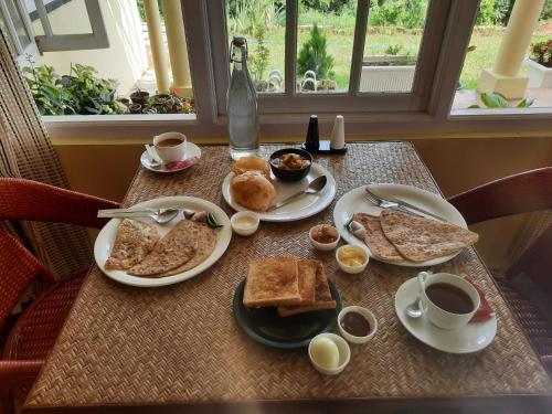 a table with plates of breakfast food on it at The Arcadia Pool and Villa - Umroi in Shillong