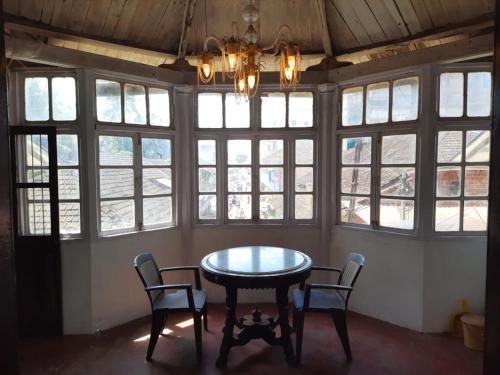 una mesa y sillas en una habitación con ventanas en Moray homestay, en Malvan