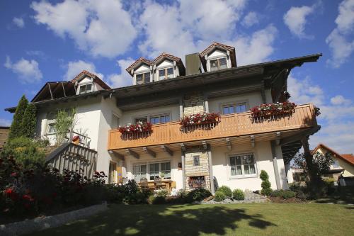 ein großes weißes Haus mit Blumenkästen auf dem Balkon in der Unterkunft Ferienwohnungen Herzog in Haundorf