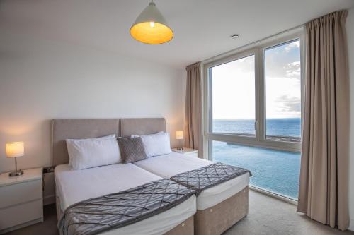 a bedroom with a bed and a large window at Unique Sea View Penthouse with Hot Tub in Brighton & Hove