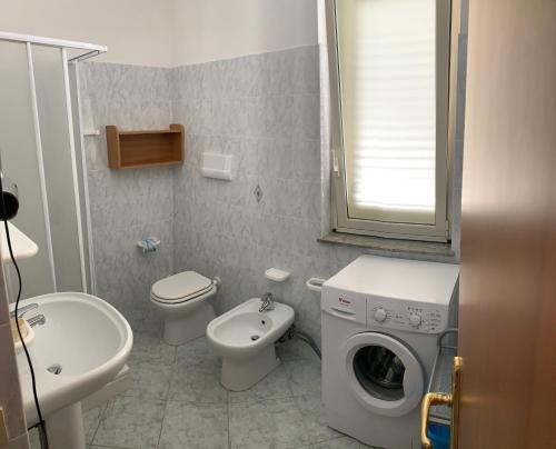 a bathroom with a toilet sink and a washing machine at Appartamento Vacanza Villetta Fichera in Gioiosa Marea