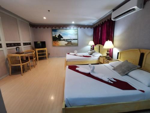 a hotel room with two beds and a table at Holiday Plaza Hotel - Cebu in Cebu City