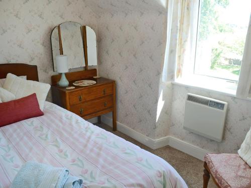 a bedroom with a bed and a dresser and a mirror at Old Midoxgate Farmhouse in Calrossie