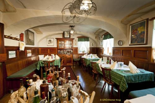 a restaurant with green tables and chairs and a chandelier at Landhaus Gritschacher in Sankt Peter in Holz